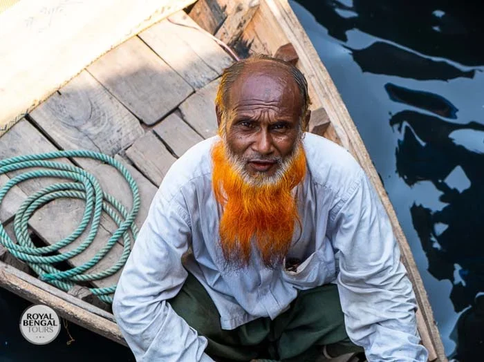 Elderly boatman with orange beard on his vessel at Sadarghat, a Dhaka river port