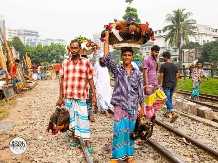 Street hawkers selling chicken in baskets on their heads at a bazaar in Old Dhaka