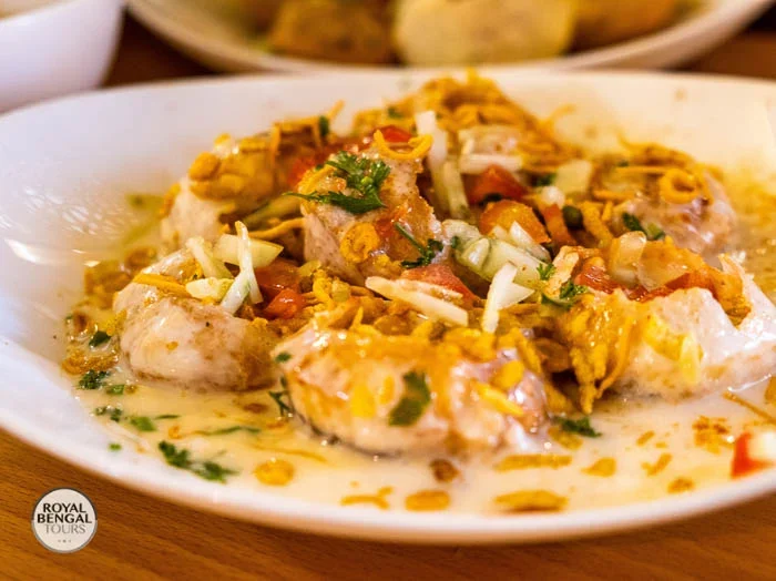 a plate of fuchka, crispy puffed spheres filled with potato and chickpea filling, served with tamarind sauce and coriander chutney